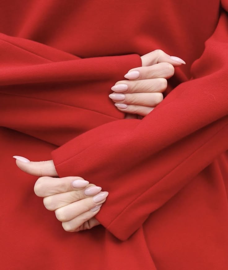 Editorial detail — hands crossed in a saturated red coat
