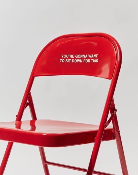 Red folding chair reading 'You're gonna want to sit down for this'